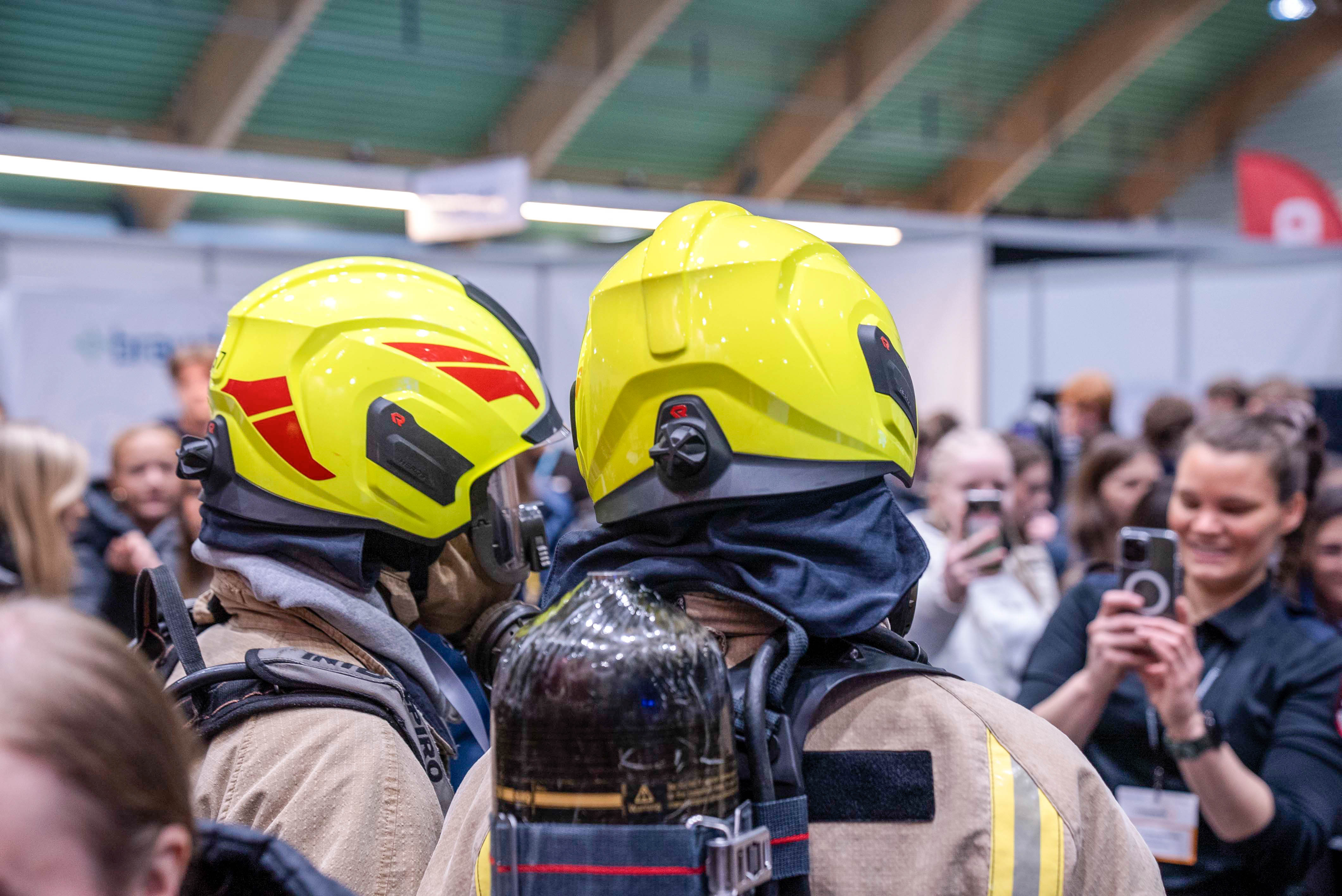 To elever i brannbekledning står med ryggen til og blir tatt bilde av
