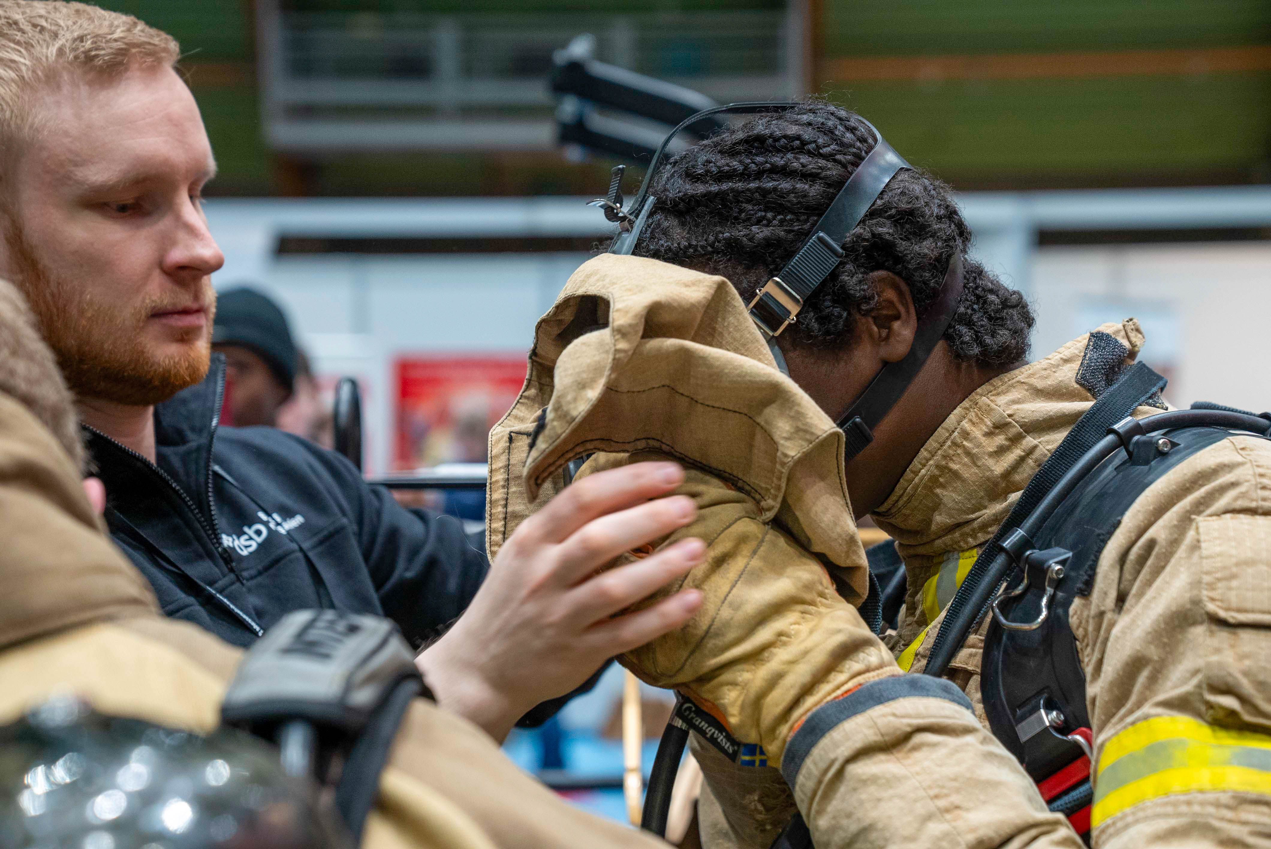 En ansatt hjelper elev med å ta på røykdykkermasse. 