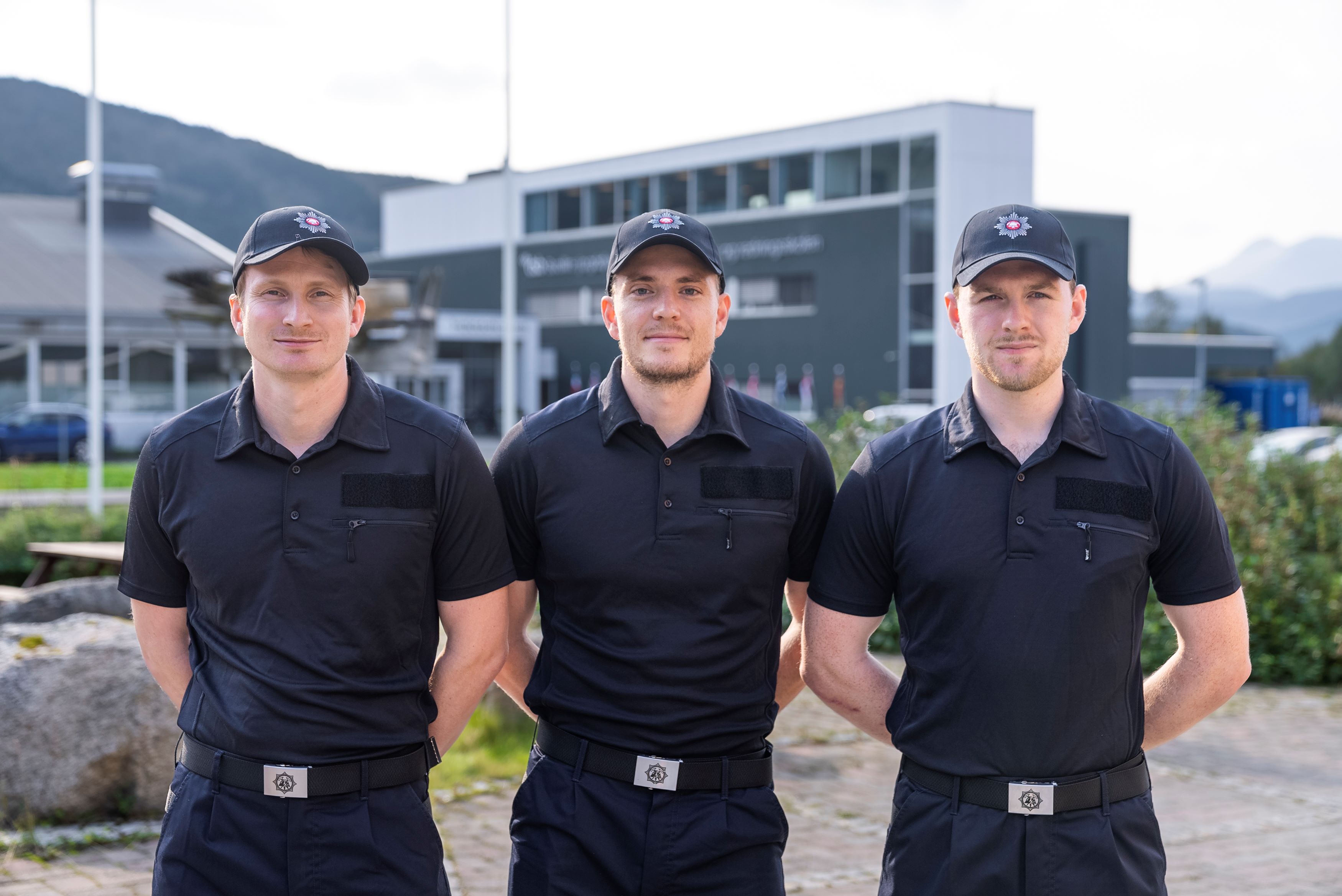 Tre studenter i uniform står oppstilt mot kamera