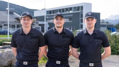 Tre studenter i uniform står oppstilt mot kamera