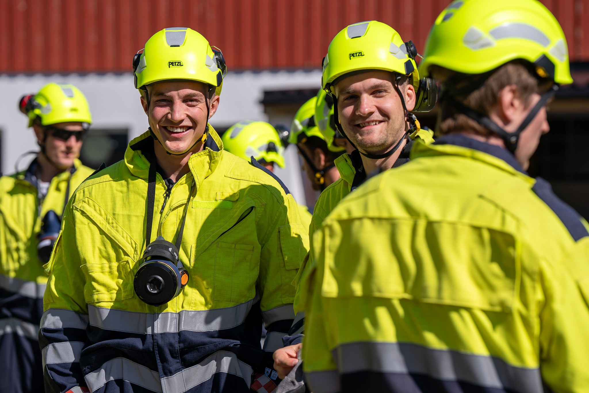 Brannkonstabelstudenter kledd i trafikkdresser smiler mot kamera