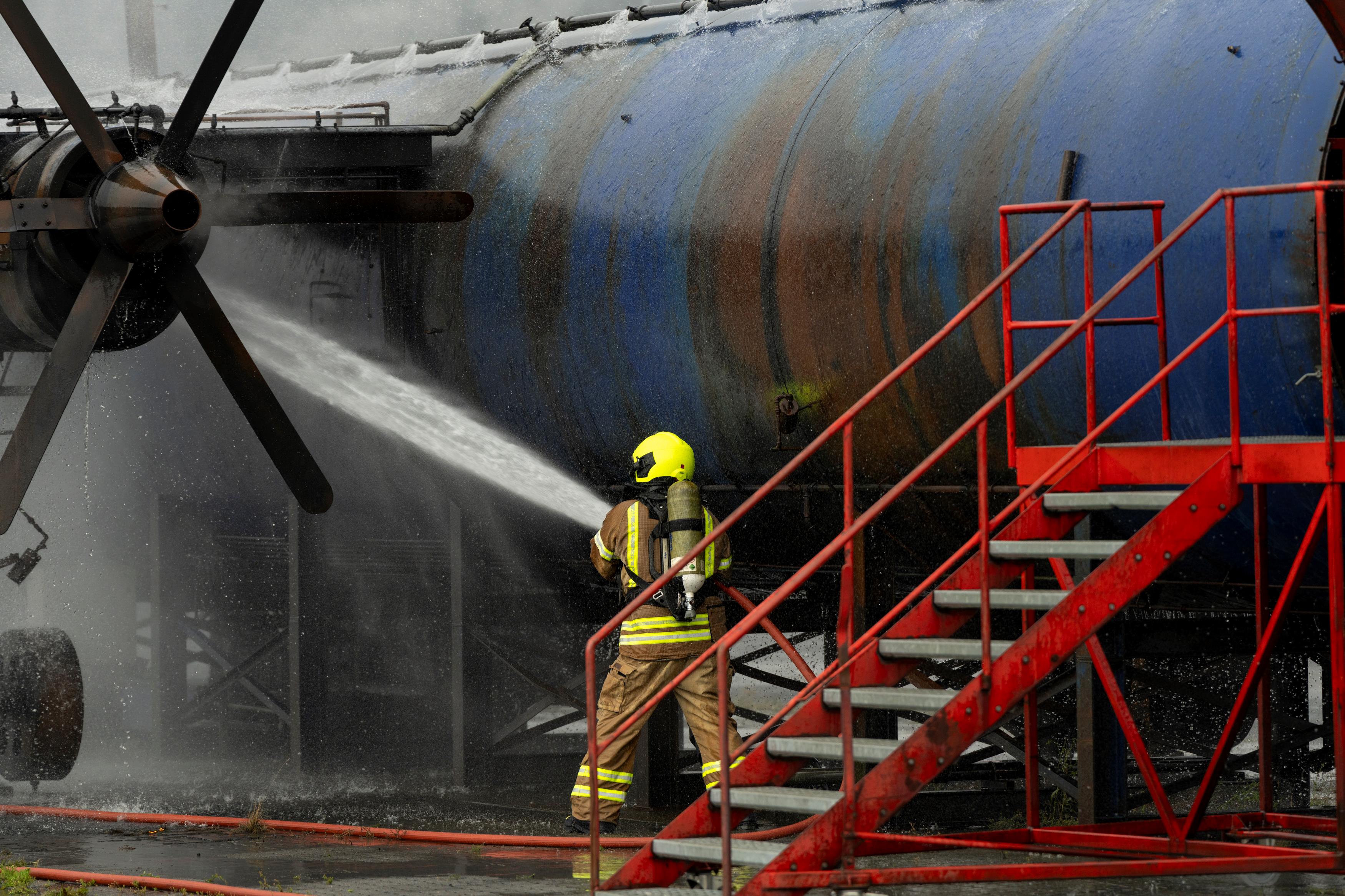 Brannkonstabel slukker brann i flymotor. Foto: BRSK