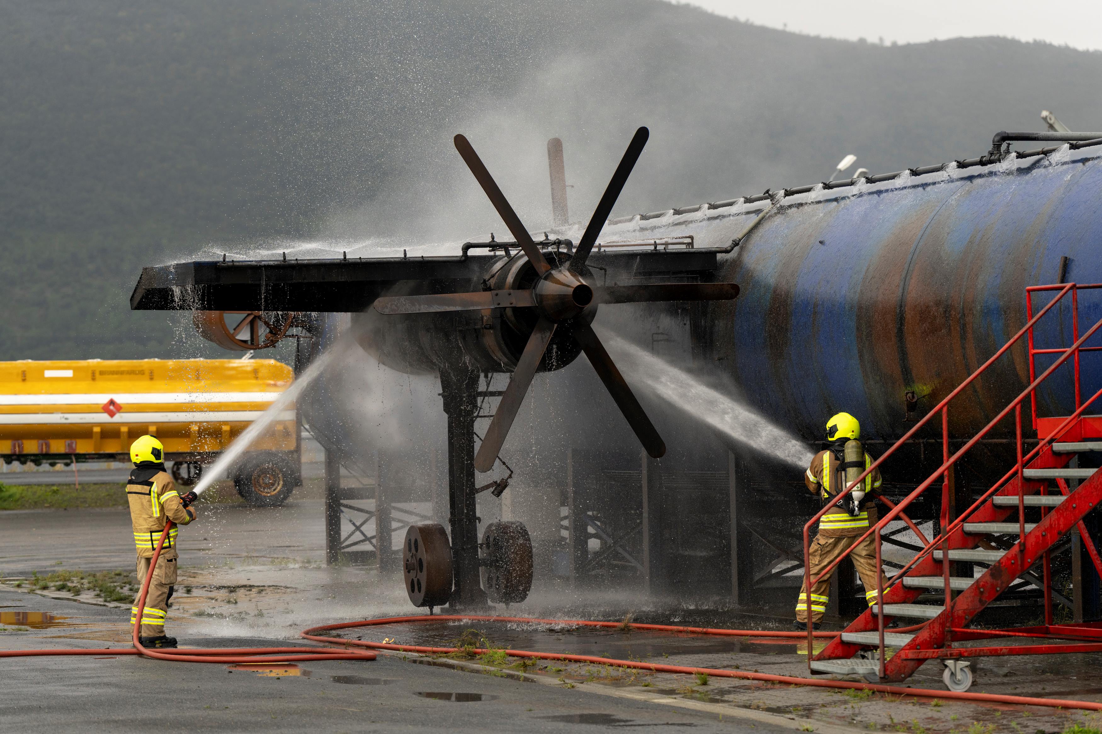 To brannkonstabler slukker brann i flykropp. Foto