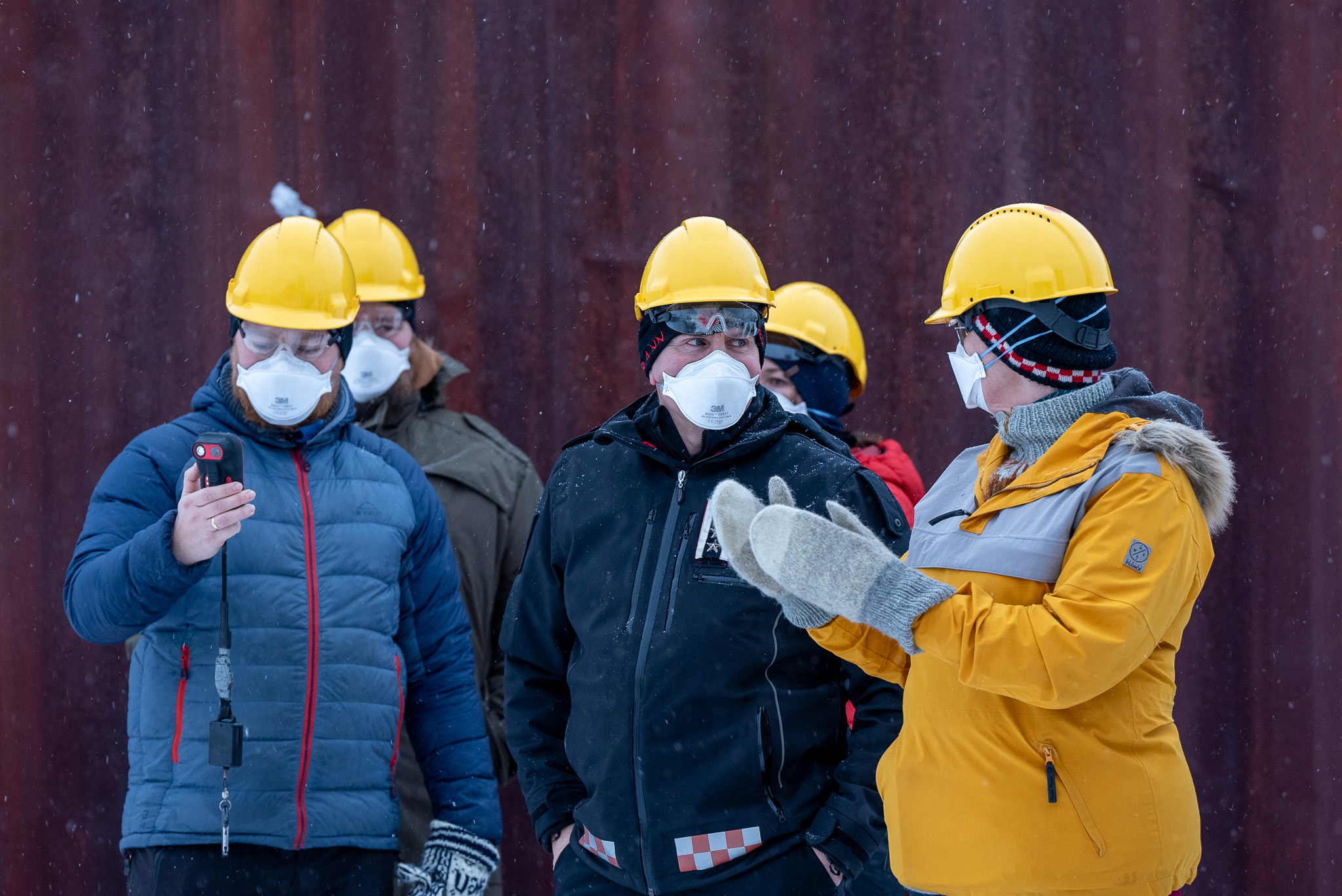 Fire mennesker med hjelm og maske har en samtale. Foto.