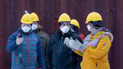 Fire mennesker med hjelm og maske har en samtale. Foto.