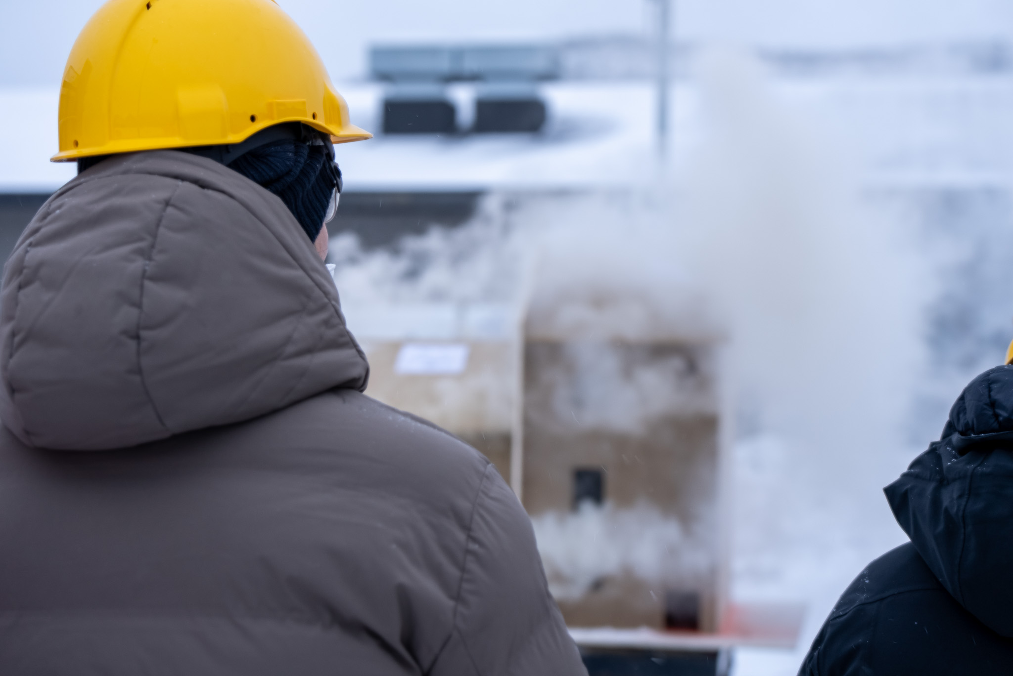 Mann med ryggen til kamera observerer røyk fra et modellhus. Foto