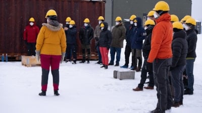 En gruppe mennesker med hjelm og maske står i halvsirkel. Foto: BRSK