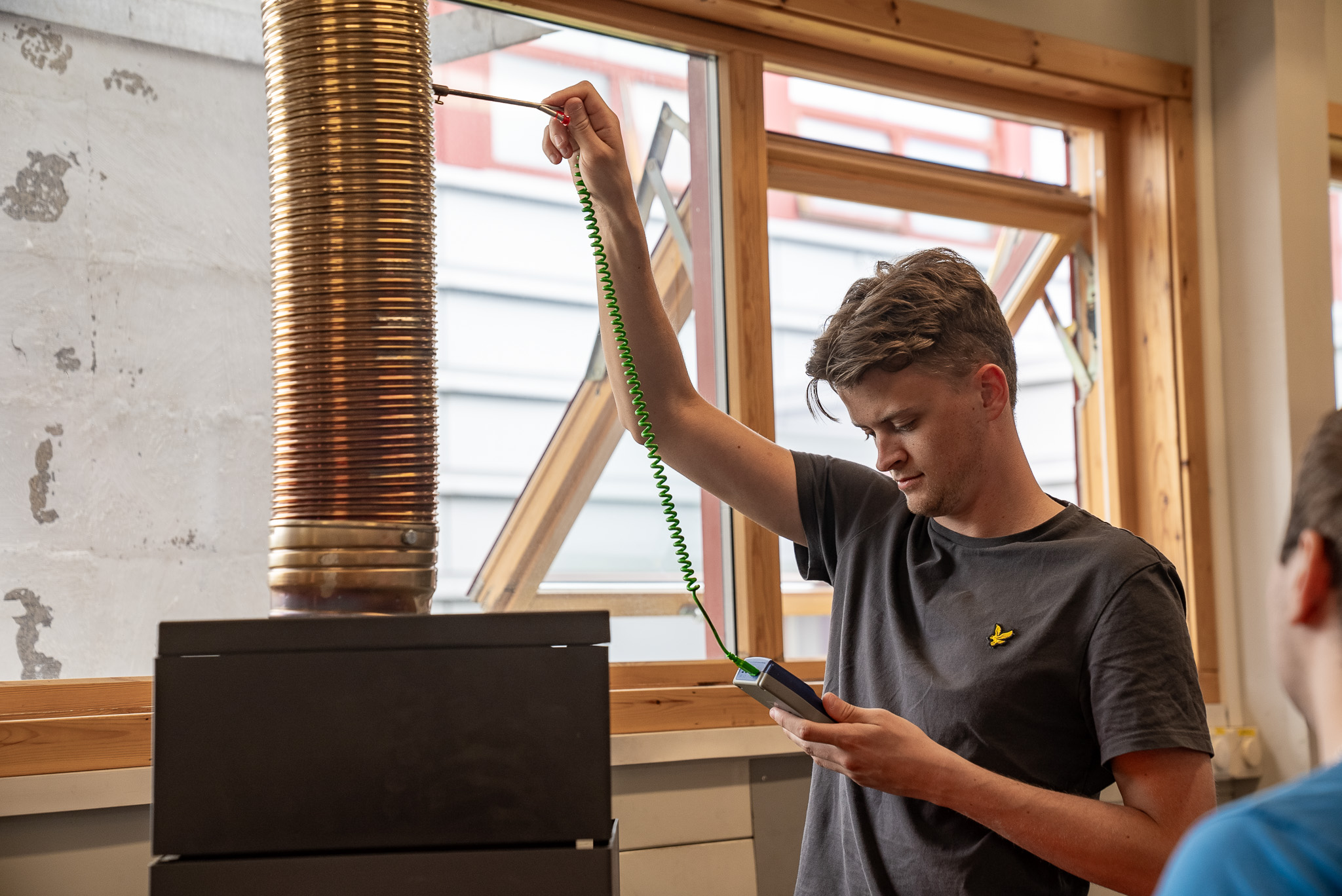 Elev måler temperaturen på røykgassen med et instrument