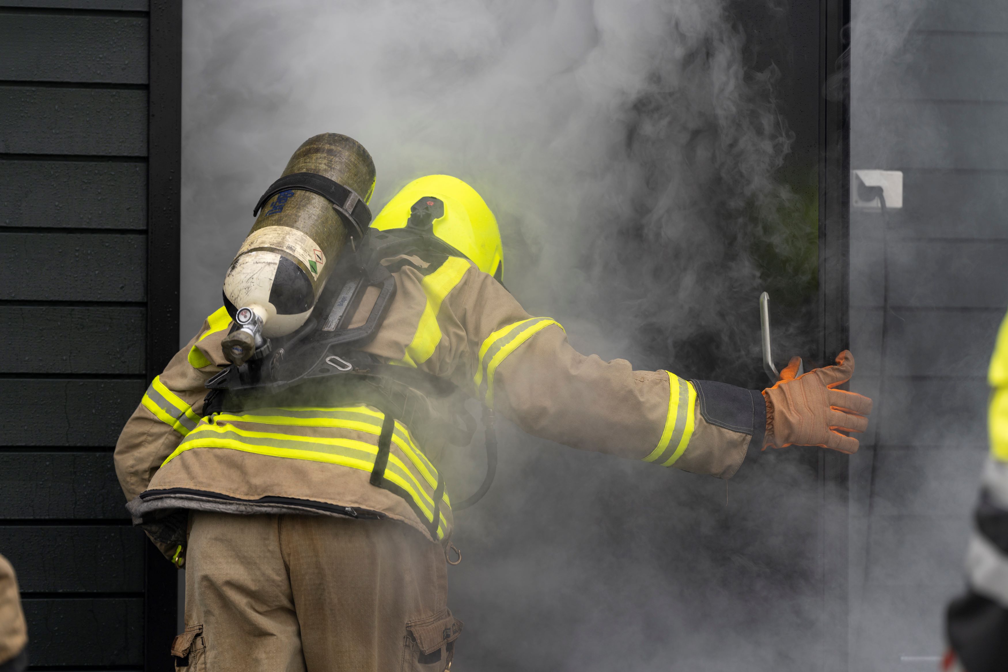 Brannkonstabel på tur inn i ei dør hvor det siver røyk ut