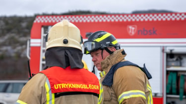 To brannkonstabler, den ene med ryggen til og teksten "utrykningsleder" på ryggen