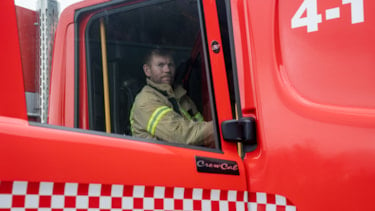 Brannkonstabel sitter i en brannbil med døren åpen og kikker i kamera
