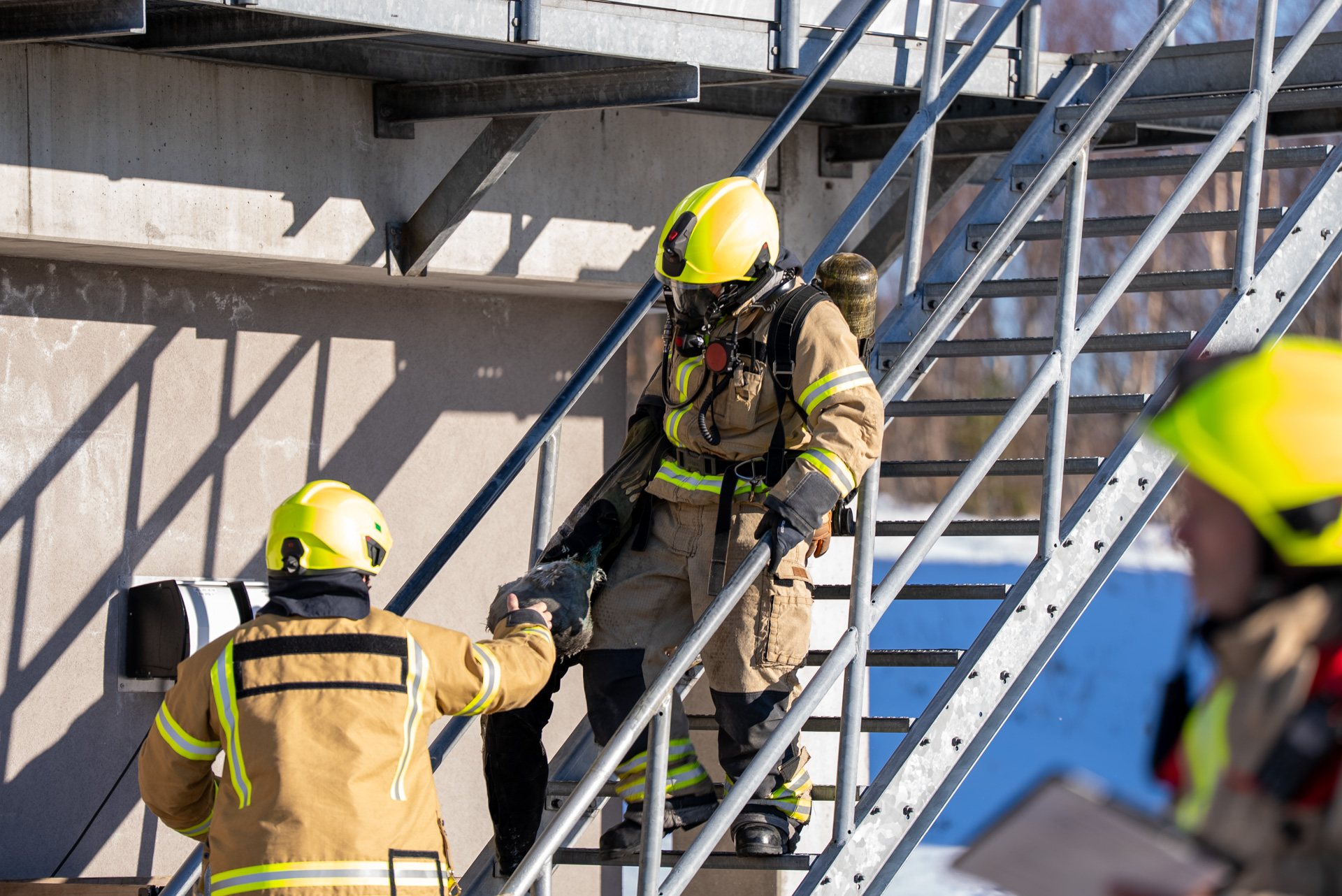 Brannkonstabel bærer dukke ned en trapp. Foto