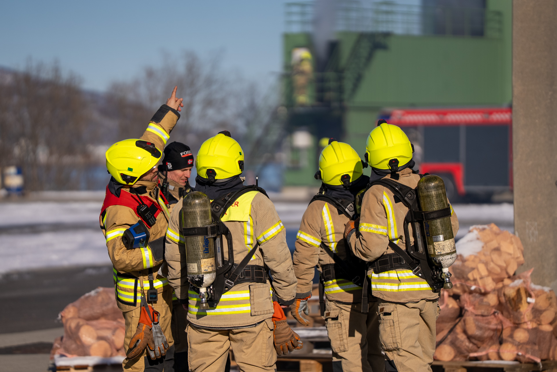 Fire brannkonstabler med ryggen til peker opp på noe utenfor bildet. Foto