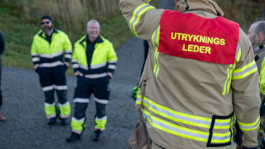 En brannkonstabel står med ryggen til kamera med teksten "utrykningsleder på ryggen"