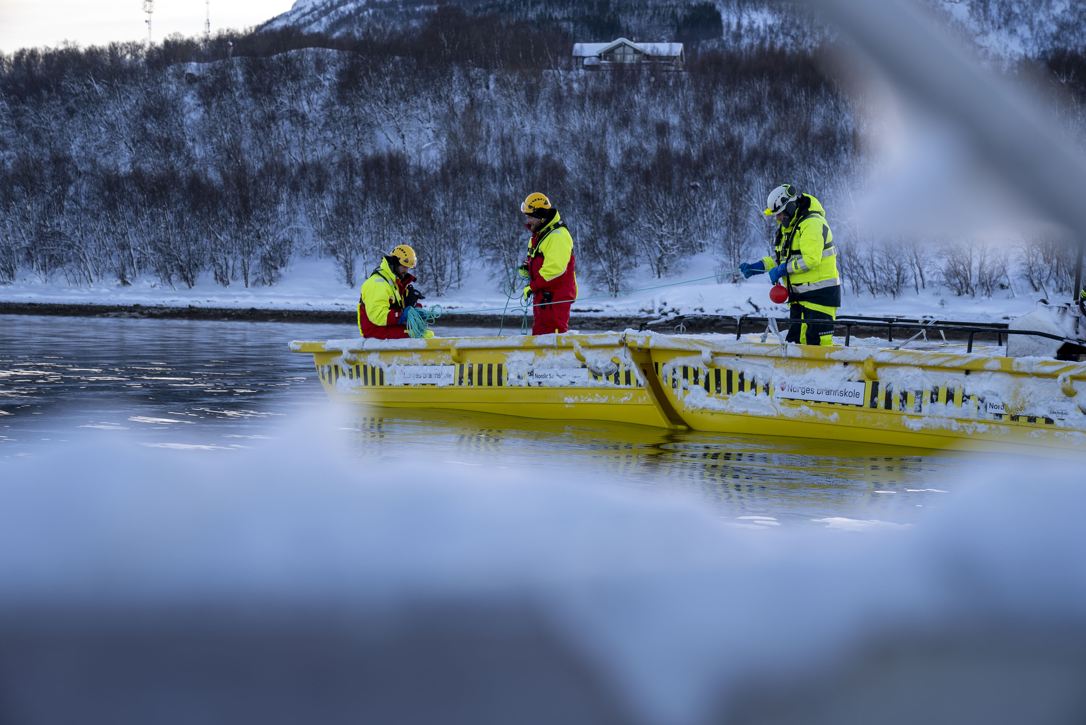 Tre menn i båt klargjør utstyr til lensesetting